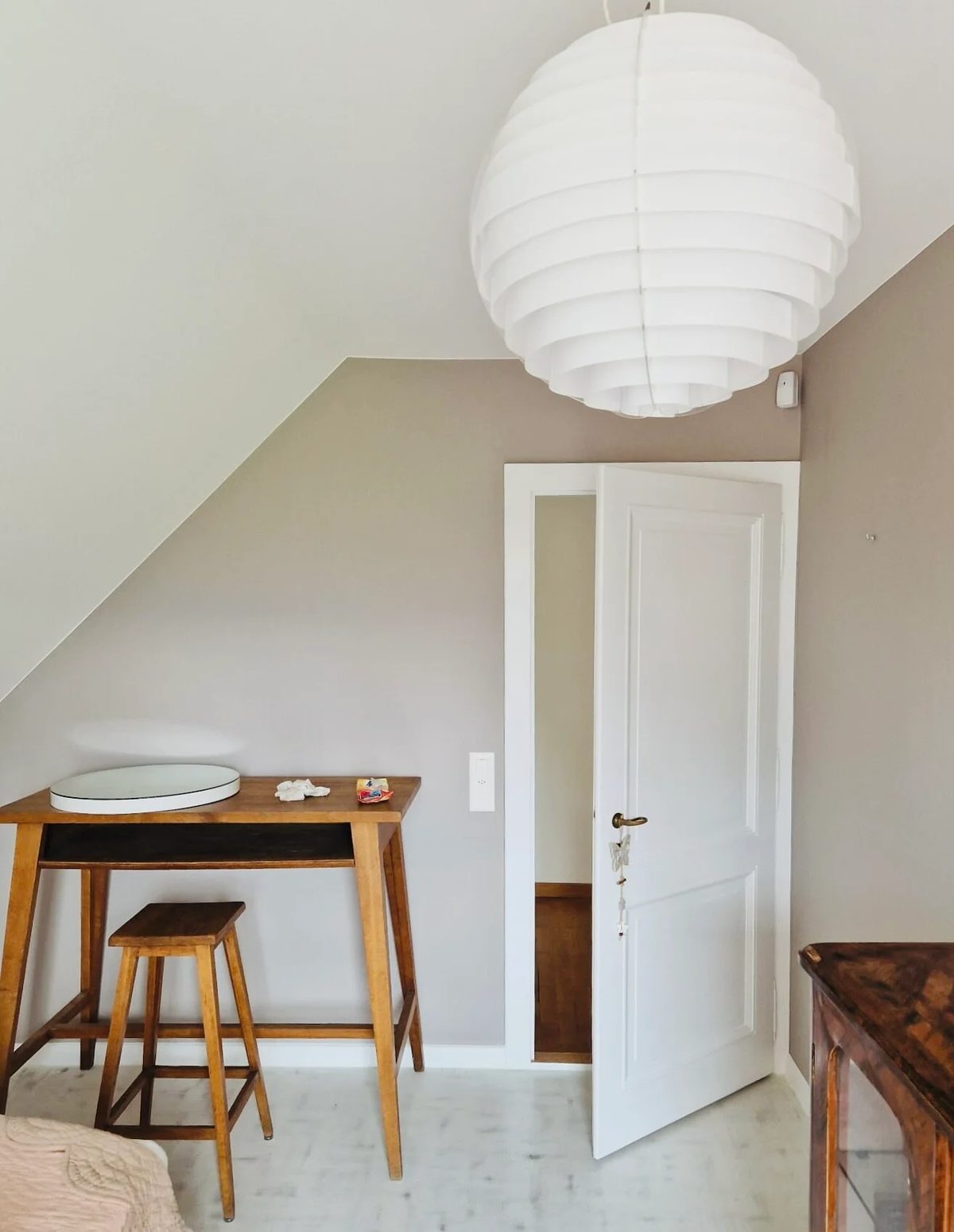 Chambre mansardée aux murs greige, plafond en pente et porte en blanc