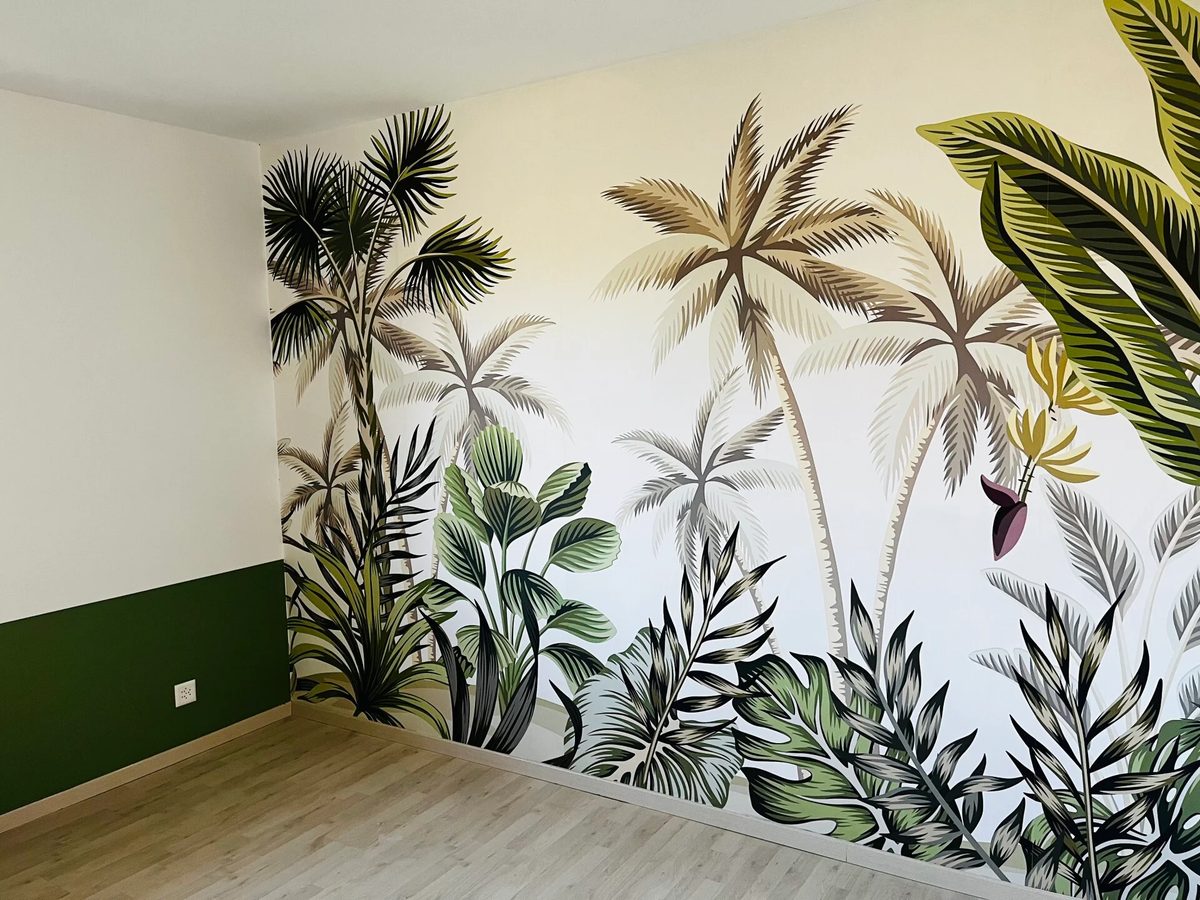 Mur habillé d’un papier peint panoramique à motif de jungle, au-dessus d’un soubassement peint en vert foncé